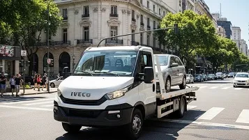 Grúa remolcando auto gris por una avenida